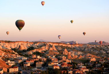 Kapadokya 'da (Türkiye) Goreme kasabası yakınlarındaki bir vadi üzerinde şafakta sıcak hava balonları uçuşu