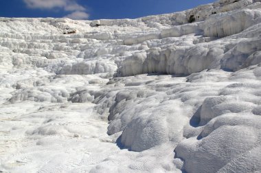 Pamukkale, Türkiye 'de bulutlu açık mavi gökyüzüne karşı insansız kar beyazı travertinin yakın plan fotoğrafı