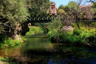 Üzerinde demir bir köprü bulunan nehir manzaralı manzara, Ihlara Vadisi, Kapadokya, Türkiye 'de arka planda orman ve dağlar