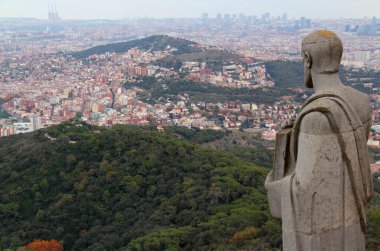 Barselona, Katalonya, İspanya - 20 Kasım 2021: Tibidabo Tepesi 'ndeki Kutsal Yürek Tapınağı' nın ön planında dini bir heykel bulunan Barcelona kentinin panoramik manzarası