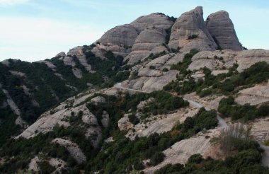 Barcelona, Katalonya, İspanya yakınlarındaki Montserrat manastırı yakınlarındaki Ulusal Parkı 'nda bulutlu mavi bir gökyüzüne karşı dağlarla manzara