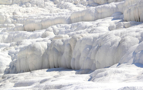 Close-up photo of snow-white travertines illuminated by the sun without people in Pamukkale, Turkey