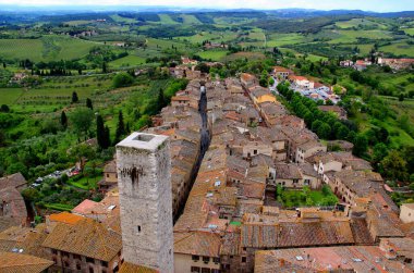 İtalya 'nın Toskana bölgesinde, Siena yakınlarındaki San Gimignano' da ortaçağ kulesi ve yeşil vadi ile şehrin tarihi kısmının en üst görüntüsü.