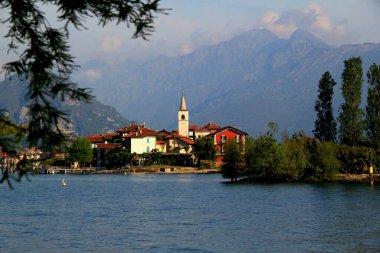 İtalya 'nın Piedmont bölgesindeki Stresa kenti yakınlarındaki dağların arka planında Lago Maggiore ve Isola dei Pescatori adası manzaralı bir manzara.