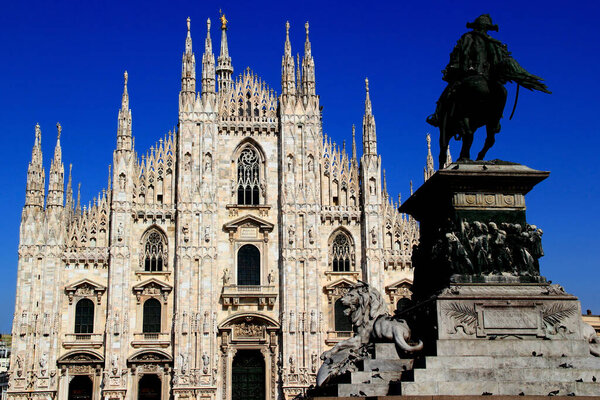 Milan, Italy - May 14, 2019: Photo with a view of the facade of the Cathedral of Duomo di Milano and the monument Statua di Vittorio Emanuele II with a lion in the foreground