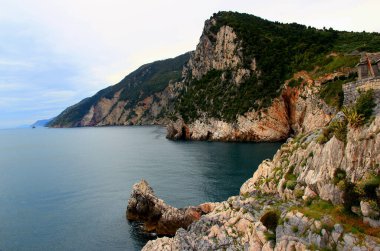Ligurian Denizi 'nin düz yüzeyi ve İtalya' nın La Spezia kenti yakınlarındaki Portovenere 'de yeşil alanları olan kayalık dağların manzarası.