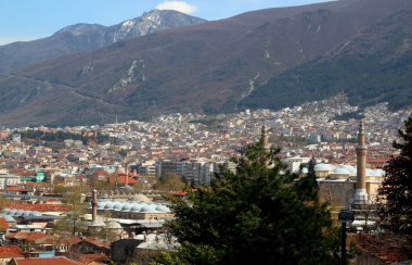 Arkasında birçok cami, hans ve Uludağ bulunan Bursa (Türkiye) kentinin panoramik manzarası bulutlu mavi bir gökyüzüne karşı