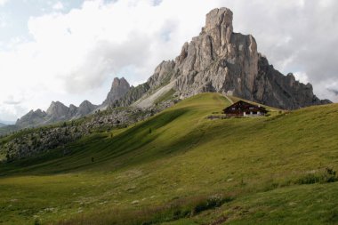 Passo Giau, Cortina d 'Ampezzo, İtalya - 22 Temmuz 2023: Yeşil çayır manzaralı manzara ve Passo Giau, Dolomites, Güney Tyrol bölgesindeki bulutlu gökyüzüne karşı bir dağ sırası