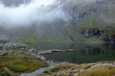 Landscape photo with a view of the lake Balea and mountains in the morning fog on Transfagarasan mountain road in Romania