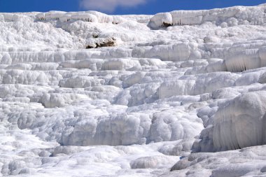 Pamukkale, Denizli, Türkiye 'de bulutlu açık mavi gökyüzüne karşı insansız kar beyazı travertinin yakın plan fotoğrafı