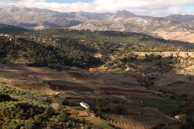 İspanya 'nın Endülüs bölgesinde, Ronda' da bulutlu bir gökyüzüne karşı arka planda vadiyi ve dağları panoramik olarak gören manzara