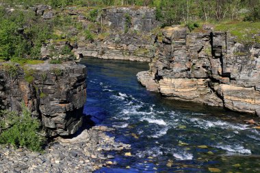 Abisko Kanyonu 'nun kayalık kıyıları ve İsveç' in kuzeyindeki Abisko Ulusal Parkı 'nın aşağısında akan nehirle manzara fotoğrafı.