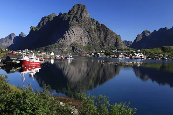 Norveç 'teki Lofoten Adaları' ndaki Reine yakınlarında sabah vakti tekneli bir körfez ve dağ manzaralı bir manzara.