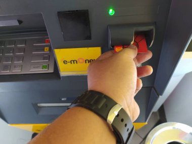 Genç bir adamın şehirdeki otomatik para makinesine kartını sokmasına yakın çekim. Para çekmek, faturaları ödemek, çek hesapları, para transferi. Gizlilik koruması, internet ve mobil güvenlik kavramı