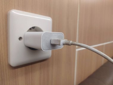 Bir prize takılı cep telefonu şarj aletinin kablosunu kapat