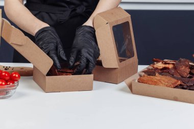 Bir adam kurutulmuş eti siyah eldivenlerle karton kutulara koyar. Yüksek kalite fotoğraf