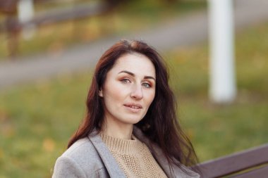 Beyaz kazaklı güzel esmer bir kızın portresi. Parktaki güzel kadın sonbahar moda ve tarzında. yüksek kaliteli fotoğraf 