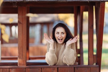 Parkta çimlerde oturan bir kadın dizüstü bilgisayarla çalışıyor. Kulaklık takan bir kadın parkta bir ağacın altında otururken dizüstü bilgisayar kullanıyor. Arkasından parlak güneş ışığı geliyor. Yüksek kalite fotoğraf