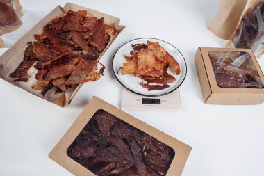 Bir adam kurutulmuş eti siyah eldivenlerle karton kutulara koyar. Yüksek kalite fotoğraf