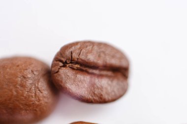 several grains of roasted coffee on a white background. macro. photographed with an old lens with blurring around the edges, and with a shallow depth of field. very large. High quality photo