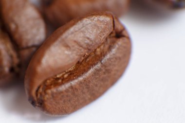 several grains of roasted coffee on a white background. macro. photographed with an old lens with blurring around the edges, and with a shallow depth of field. very large. High quality photo