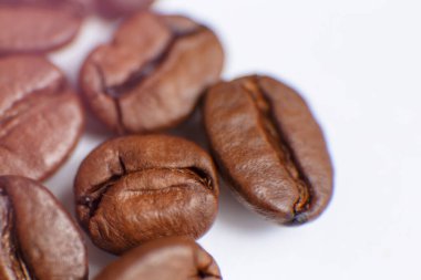 several grains of roasted coffee on a white background. macro. photographed with an old lens with blurring around the edges, and with a shallow depth of field. very large. High quality photo