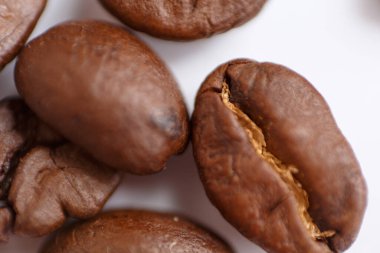 several grains of roasted coffee on a white background. macro. photographed with an old lens with blurring around the edges, and with a shallow depth of field. very large. High quality photo