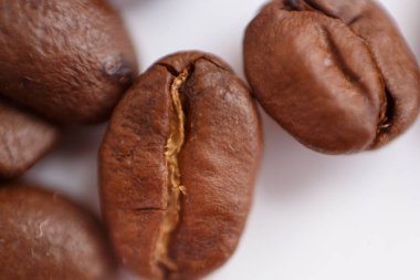 several grains of roasted coffee on a white background. macro. photographed with an old lens with blurring around the edges, and with a shallow depth of field. very large. High quality photo
