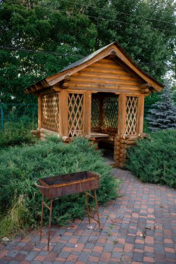 Pavilion for barbecue or wedding ceremony on the background of the forest. Wooden gazebo by the water. Place for barbecue or wedding ceremony. High quality photo