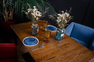 Interior design of stylish dining room interior with family wooden table, modern chairs, plate with nuts, salt and pepper shakers. Concrete floor. White wall. Template. High quality photo