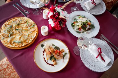 Baked pears with syrup on plate, bowl with cream and cup of tea on color wooden background. High quality photo