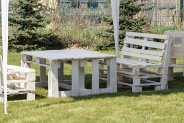 Beyaz çarşaf ya da ahşap masalı pavyon, banklar ve çiçek buketi doğal bir bahçedeki çayırda, cennet gibi bir yazlık yer güneşten ve yağmurdan, kopyalama alanından, seçilmiş odak noktadan koruma sağlar. Yüksek