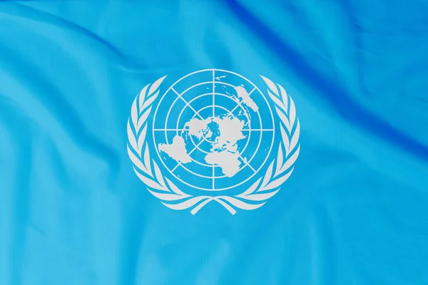 以天然物质折皱为背景的联合国旗帜 — 图库照片