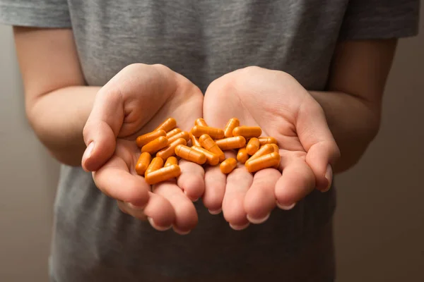 stock image Woman hands hold handful of orange turmeric pills, healthy supplements, concept of wellness, selective focus close up shot