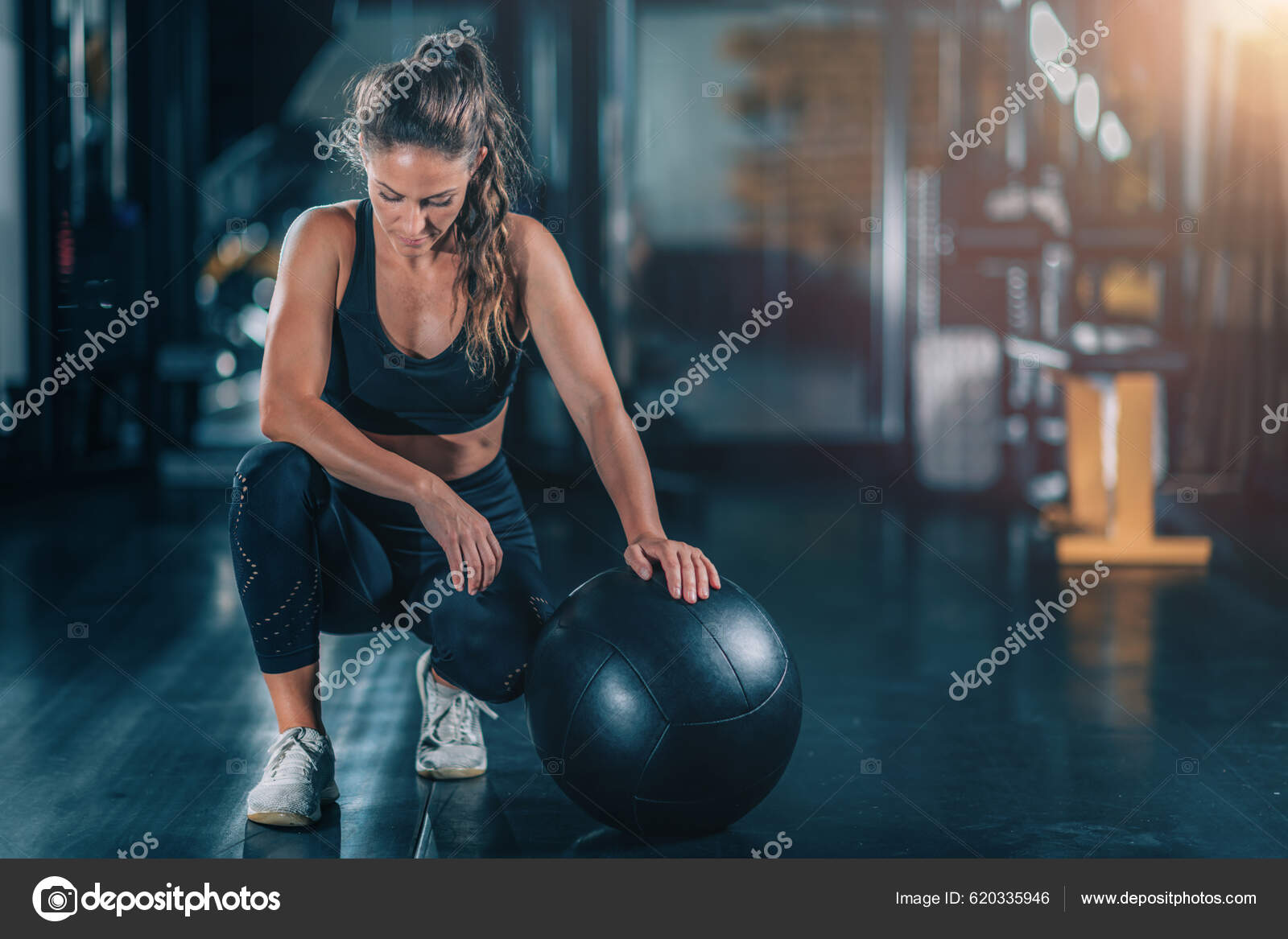 Female Athlete Exercising Wall Ball Stock Photo by microgen 620335946