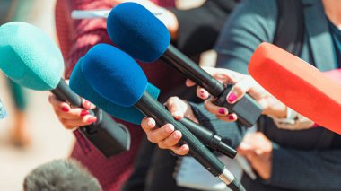 Gazeteciler dışarıda tanınmayan insanlarla röportaj yapıyor.