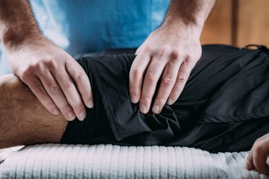 Erkek bir atletin yaralı bacağına masaj yapan fizyoterapist. Spor yaralanması fizik tedavi.