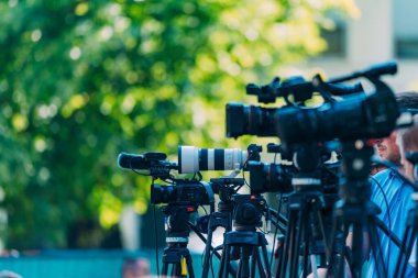 Cameras at a media conference outdoors. clipart
