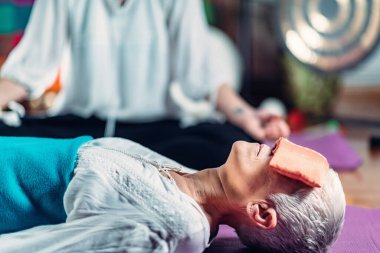 Rehberli meditasyon. Yaşlı kadın ve orta yaşlı kadın yerde uzanıp meditasyon yapıyorlar.