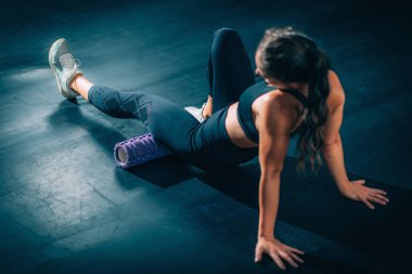 Woman Using Foam Roller to Self-Massage Muscles in the gym