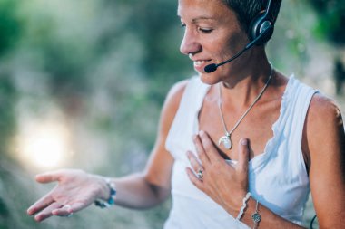 Uzaktan tedavi. İnternette bir müşteriyle çalışan kişisel geliştirme koçu, açık havada oturup olumlu duygular yolluyor.  