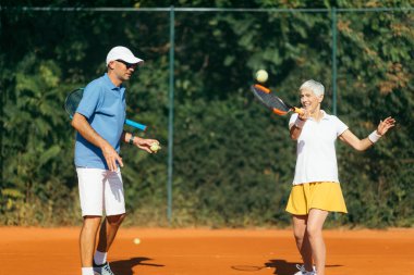 Yaşlı bir kadınla tenis hocası, tenis antrenmanı dersi.