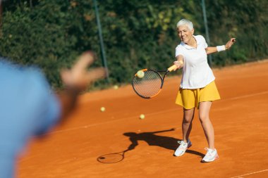 Yaşlı bir kadınla tenis hocası, tenis antrenmanı dersi.