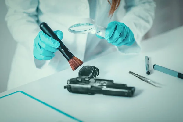Forensic Science in Lab. Forensic Scientist examining gun with evidences