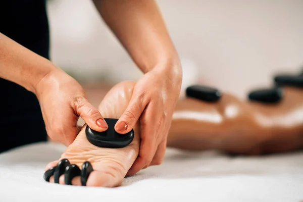 Hot Stone Foot Massage Terapeut Lindrar Spänningar Från Kundernas Fötter — Stockfoto