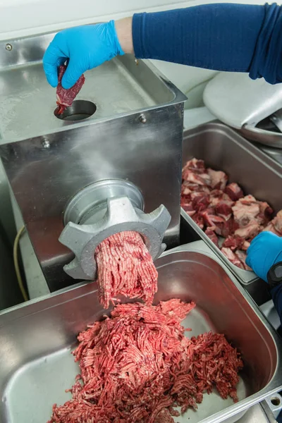 Minced beef meat in a professional grinding machine in a large restaurant close up