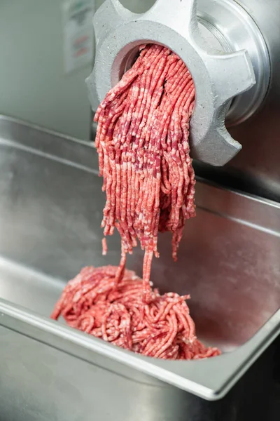 Meat grinder with minced red beef meat in a large restaurant, close up