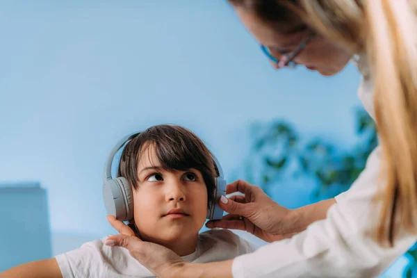 纯音测听测试 检查孩子听不同音高和音量的能力 男孩儿带着耳机 用不同的音色和音量听着声音 并作出反应 — 图库照片