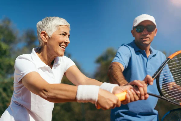 Olgun kadın eğitmeniyle tenis oynuyor.