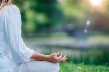 Su kenarında meditasyon. Suda meditasyon yapan genç bir kadın, yoga yaptıktan sonra dinlenme, yeşil doğa geçmişi..